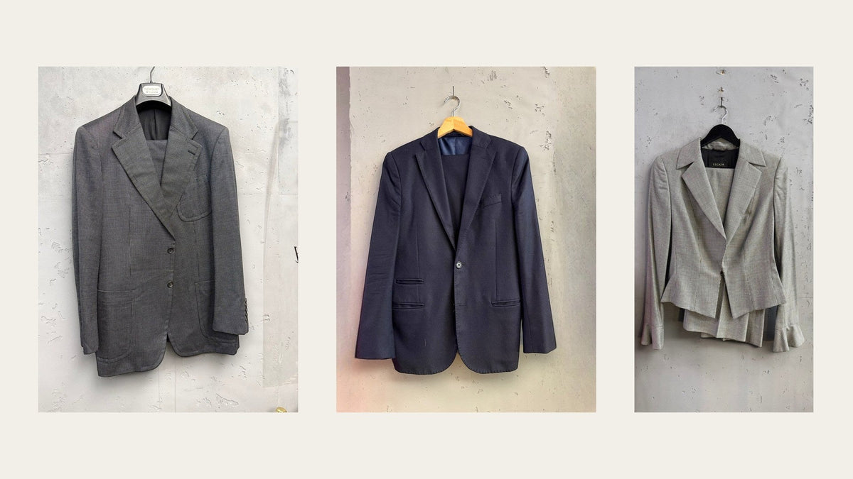 Three vintage suits on hangers at Berlin Vintage Corner: a grey Yves Saint Laurent suit, a navy two piece suit and a houndstooth Escada suit