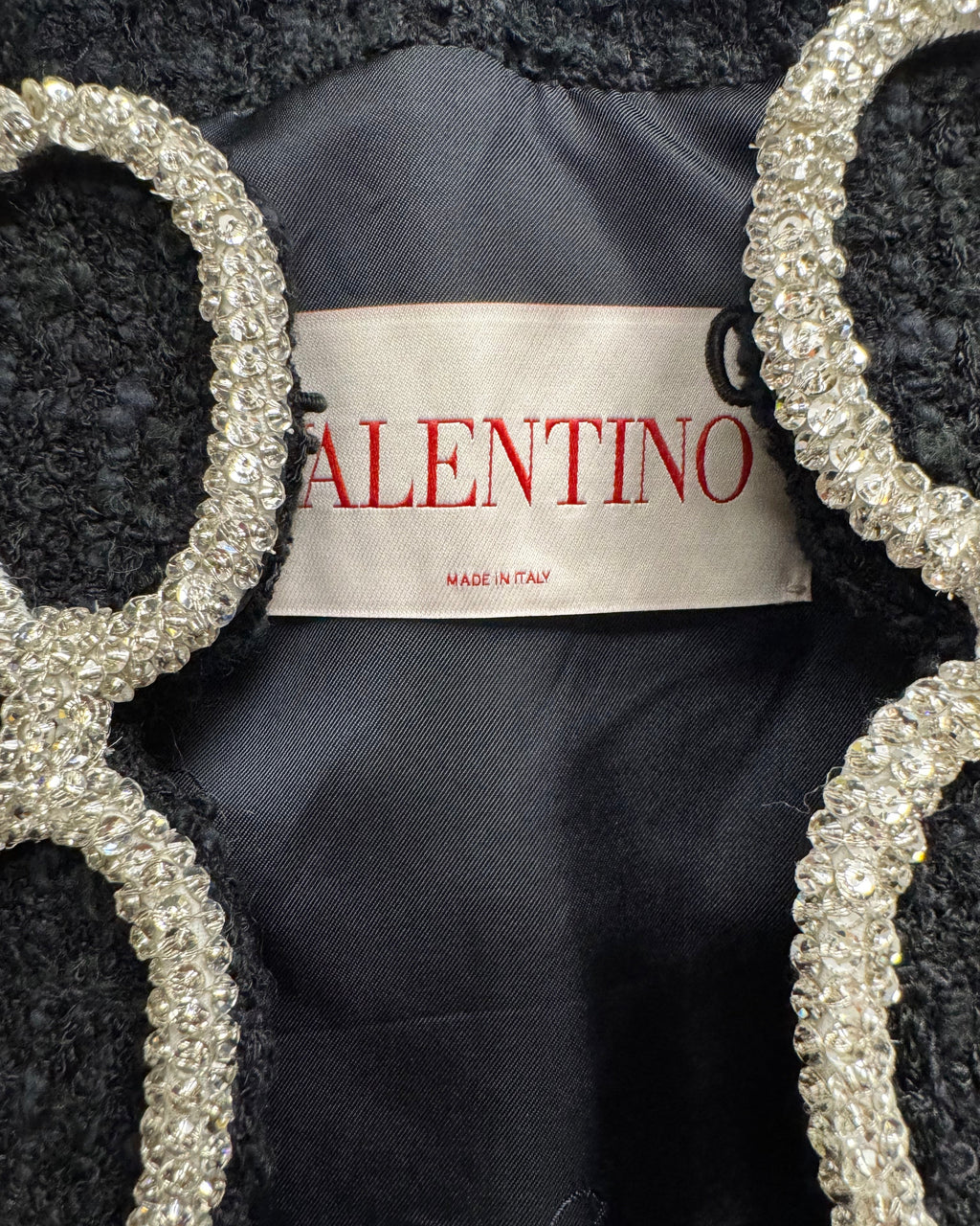 Valentino label on a black garment with decorative silver frames.