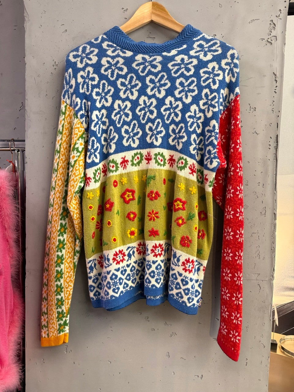 BERLIN VINTAGE CORNER blue knit sweater with abstract floral pattern, red & green accents, and yellow/green stripes. Ribbed crew neck & cuffs.