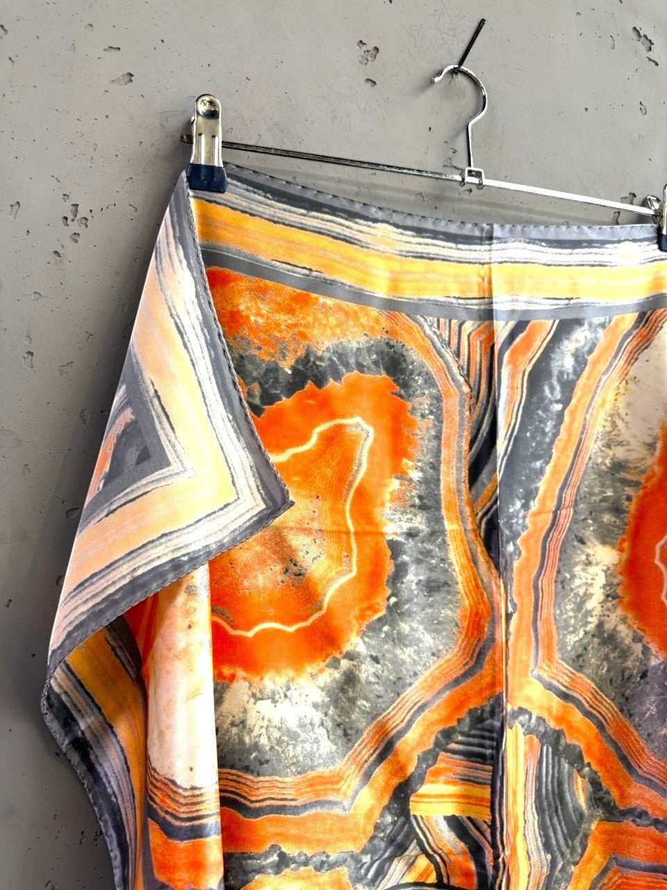 BERLIN VINTAGE CORNER silk scarf with burnt orange, charcoal, and cream geode-inspired abstract print on a hanger.