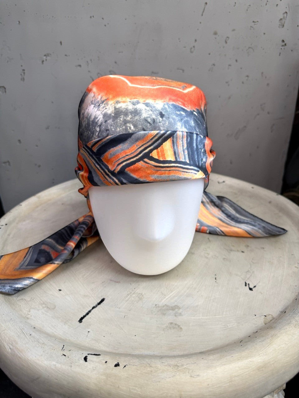 BERLIN VINTAGE CORNER silk scarf with abstract geode print in burnt orange, charcoal, and cream on a mannequin head.