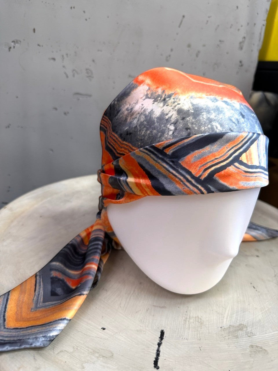 BERLIN VINTAGE CORNER silk scarf with abstract geode print in burnt orange, charcoal, and cream on a mannequin head.