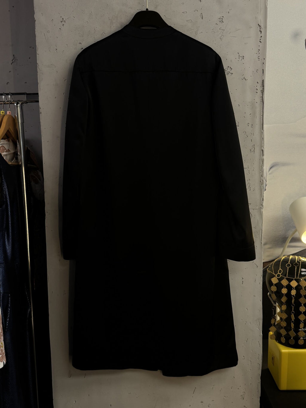 BERLIN VINTAGE CORNER Agnona black longline collarless coat hanging against a textured wall