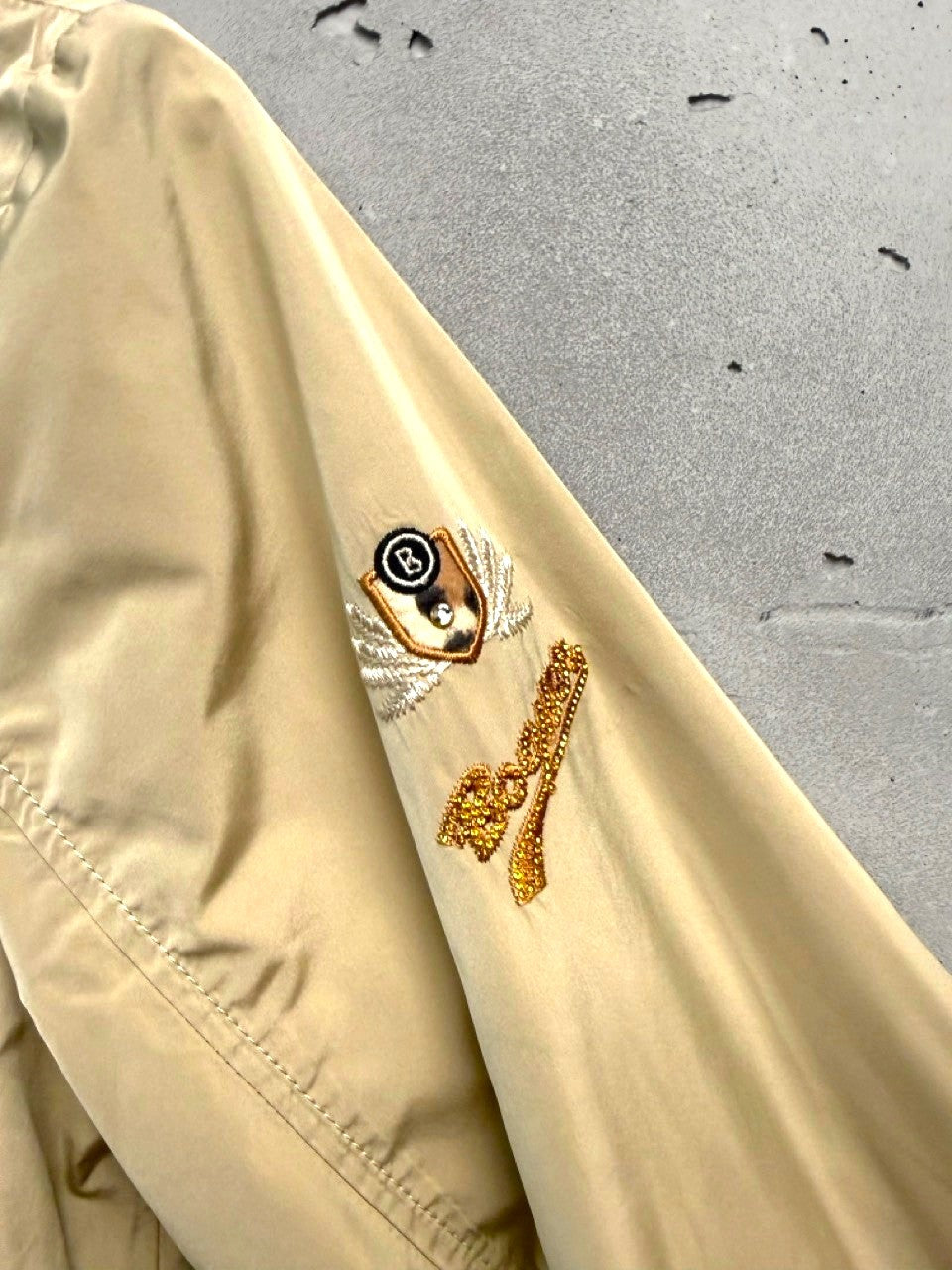 BERLIN VINTAGE CORNER beige utility jacket with embroidered crest and beaded detail on sleeve. Water-resistant fabric.