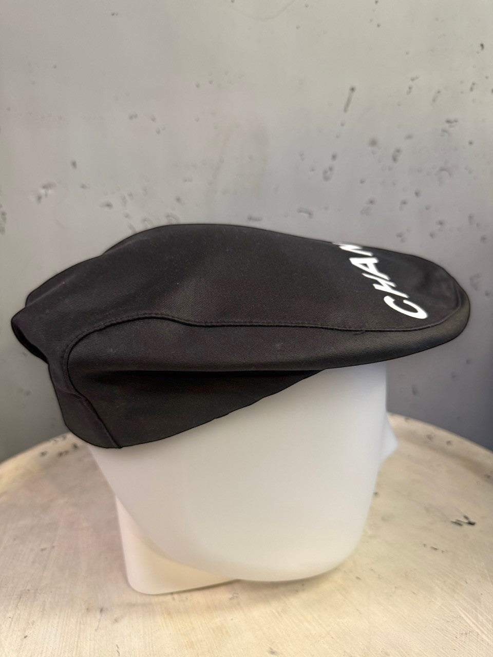BERLIN VINTAGE CORNER black CHANEL newsboy cap with white logo lettering on a white mannequin head