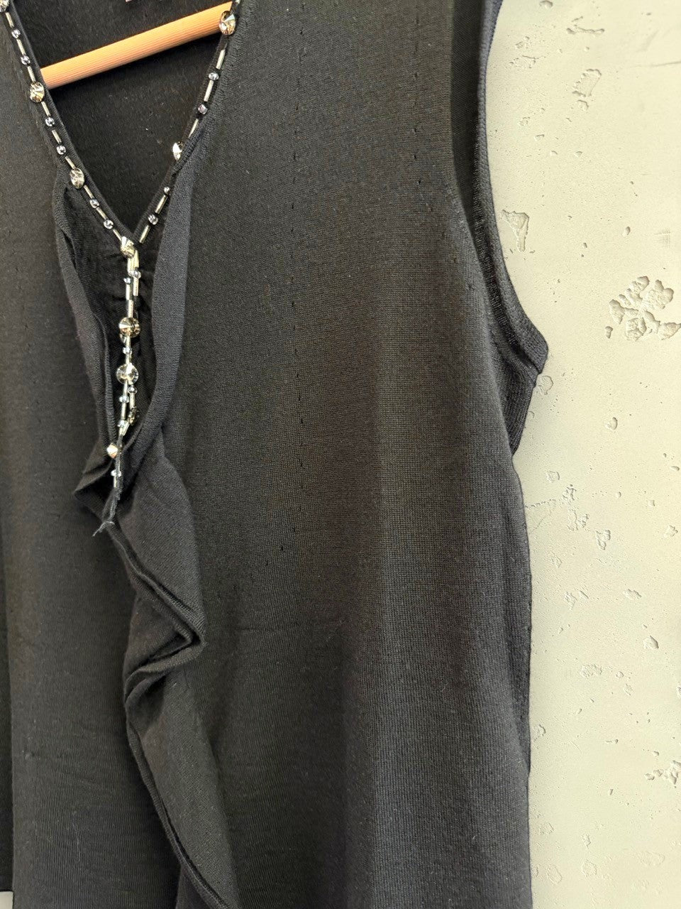 BERLIN VINTAGE CORNER black sleeveless knit V-neck top with crystal and bead embellishments and ruffled detail.