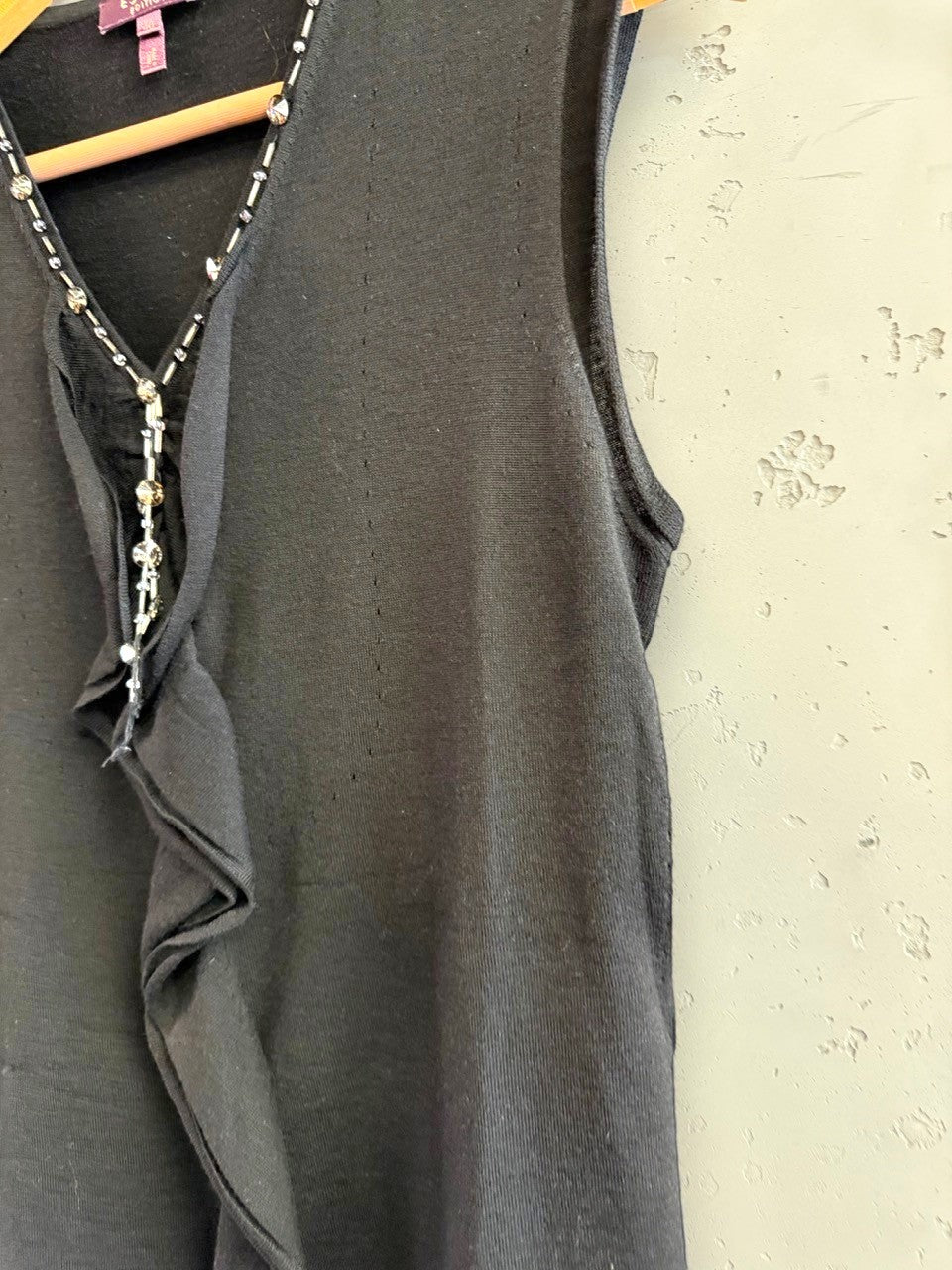 BERLIN VINTAGE CORNER black sleeveless knit V-neck top with crystal and bead embellishments and ruffled front detail.