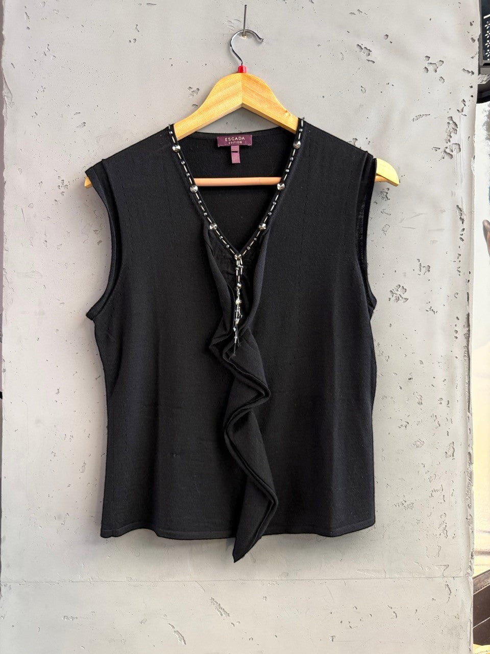 BERLIN VINTAGE CORNER black sleeveless knit V-neck top with crystal and bead embellishments and ruffled front.