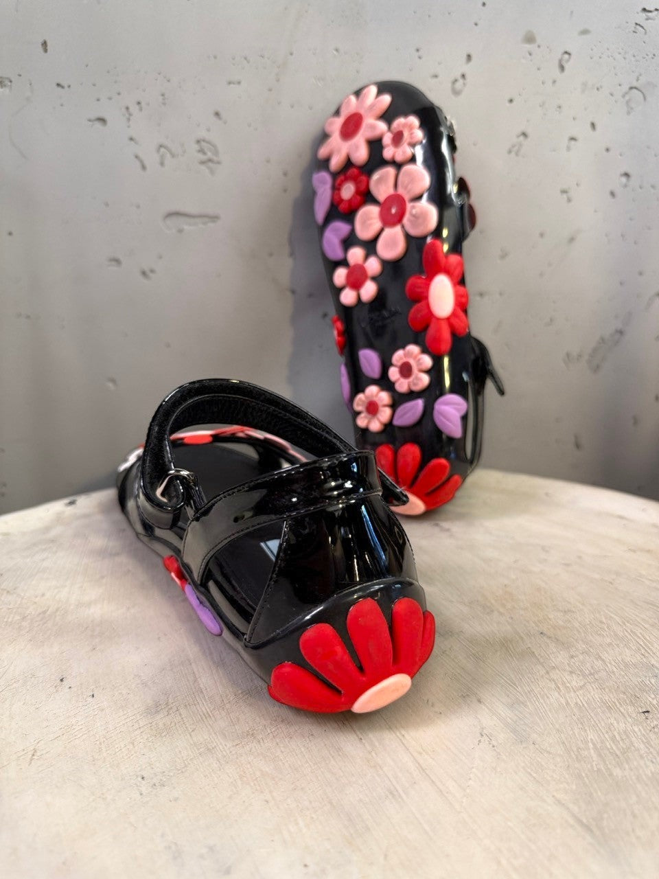 BERLIN VINTAGE CORNER black jelly sandals with red, pink, and purple floral appliqués and lilac leaves. Open-toe with ankle strap.