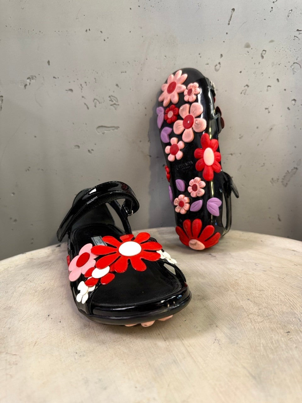 BERLIN VINTAGE CORNER black jelly sandals with red, pink, and purple floral appliqués and lilac leaves. Open-toe design with ankle strap.