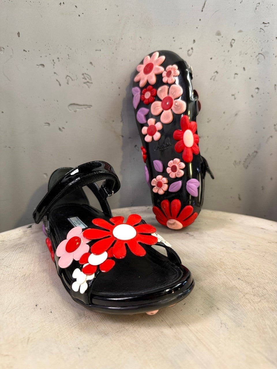 BERLIN VINTAGE CORNER black jelly sandals with red, pink, and purple floral appliqués and lilac leaves. Open-toe design with ankle strap.