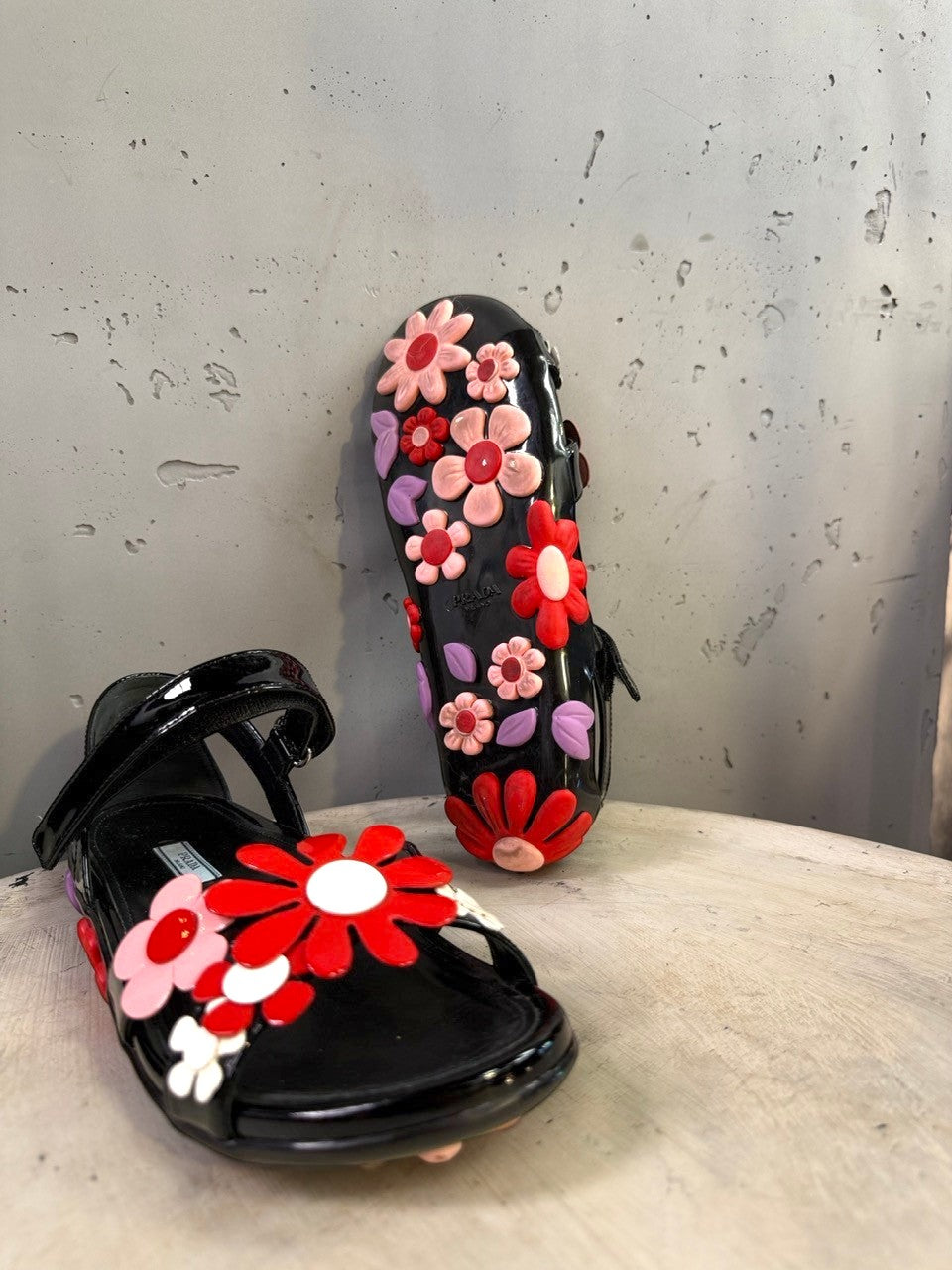BERLIN VINTAGE CORNER black jelly sandals with red, pink, and purple floral appliqués and lilac leaves. Open-toe with ankle strap.