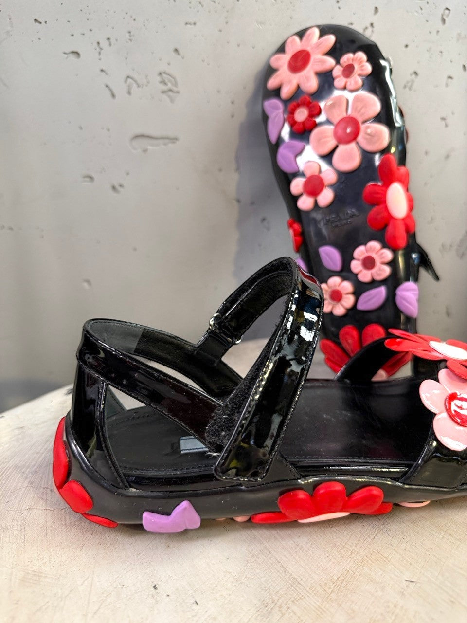 BERLIN VINTAGE CORNER black jelly sandals with red, pink, and purple floral appliqués and lilac leaves.