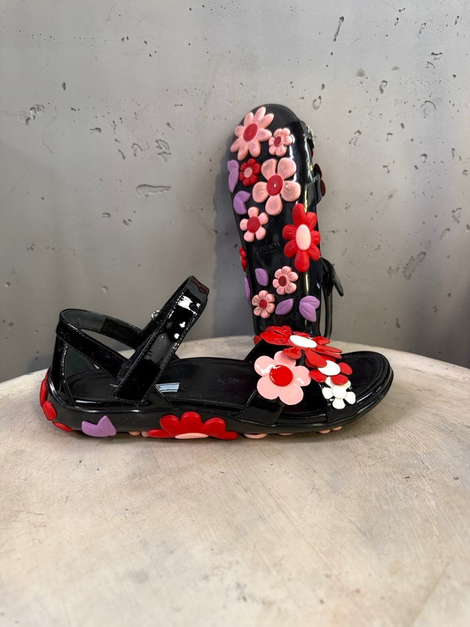 BERLIN VINTAGE CORNER black jelly sandals with red, pink, and purple flower appliqués and lilac leaves. Open-toe with ankle strap.
