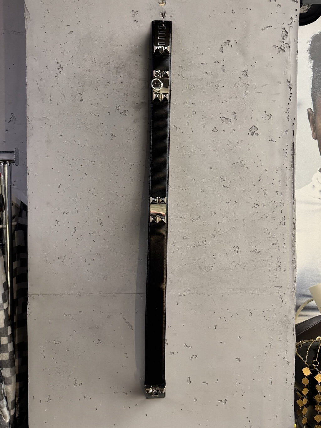 BERLIN VINTAGE CORNER black leather waist belt with silver pyramid studs and ring detail hanging on a concrete wall