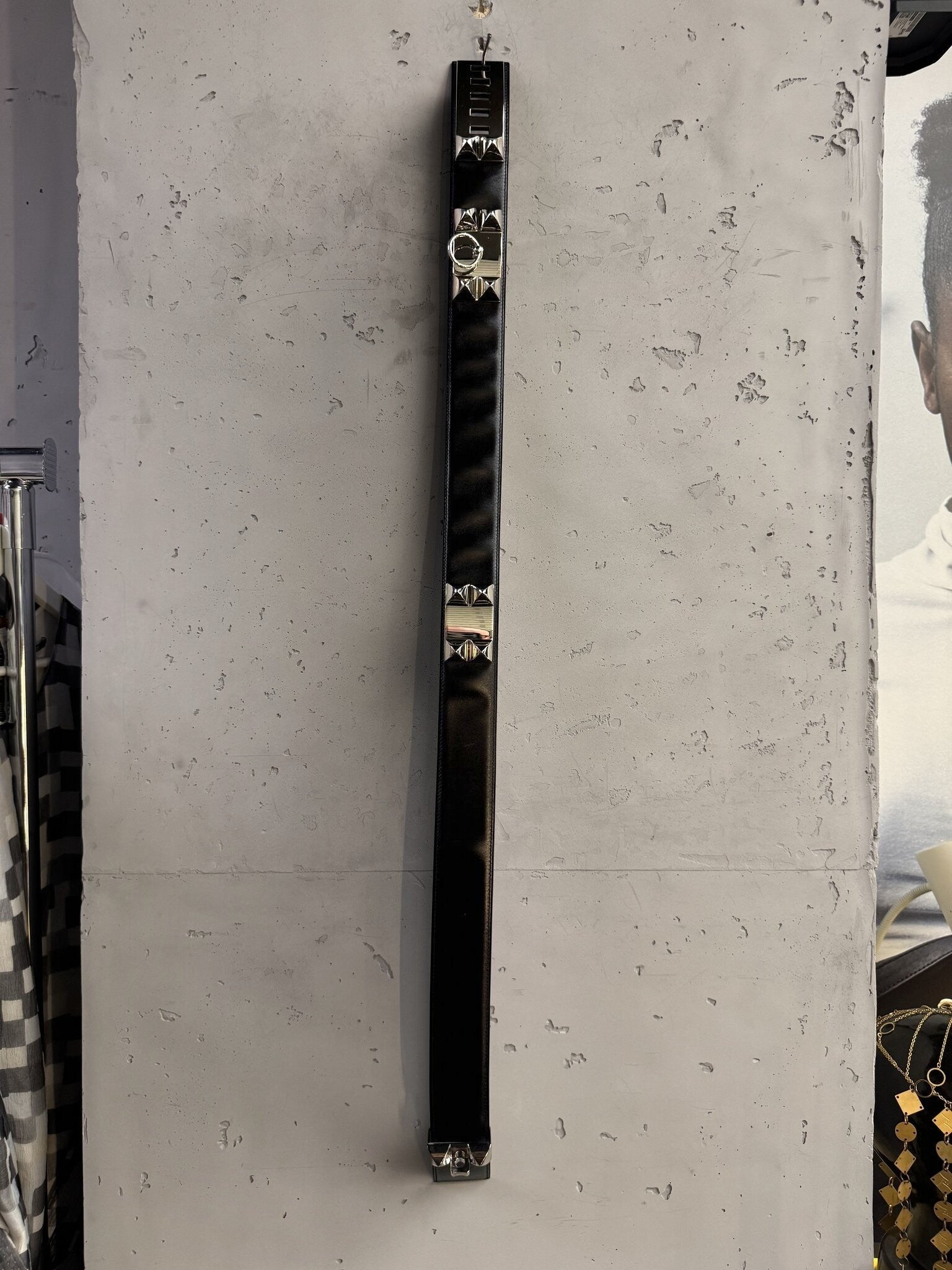 BERLIN VINTAGE CORNER black leather waist belt with silver pyramid studs and ring detail hanging on a concrete wall