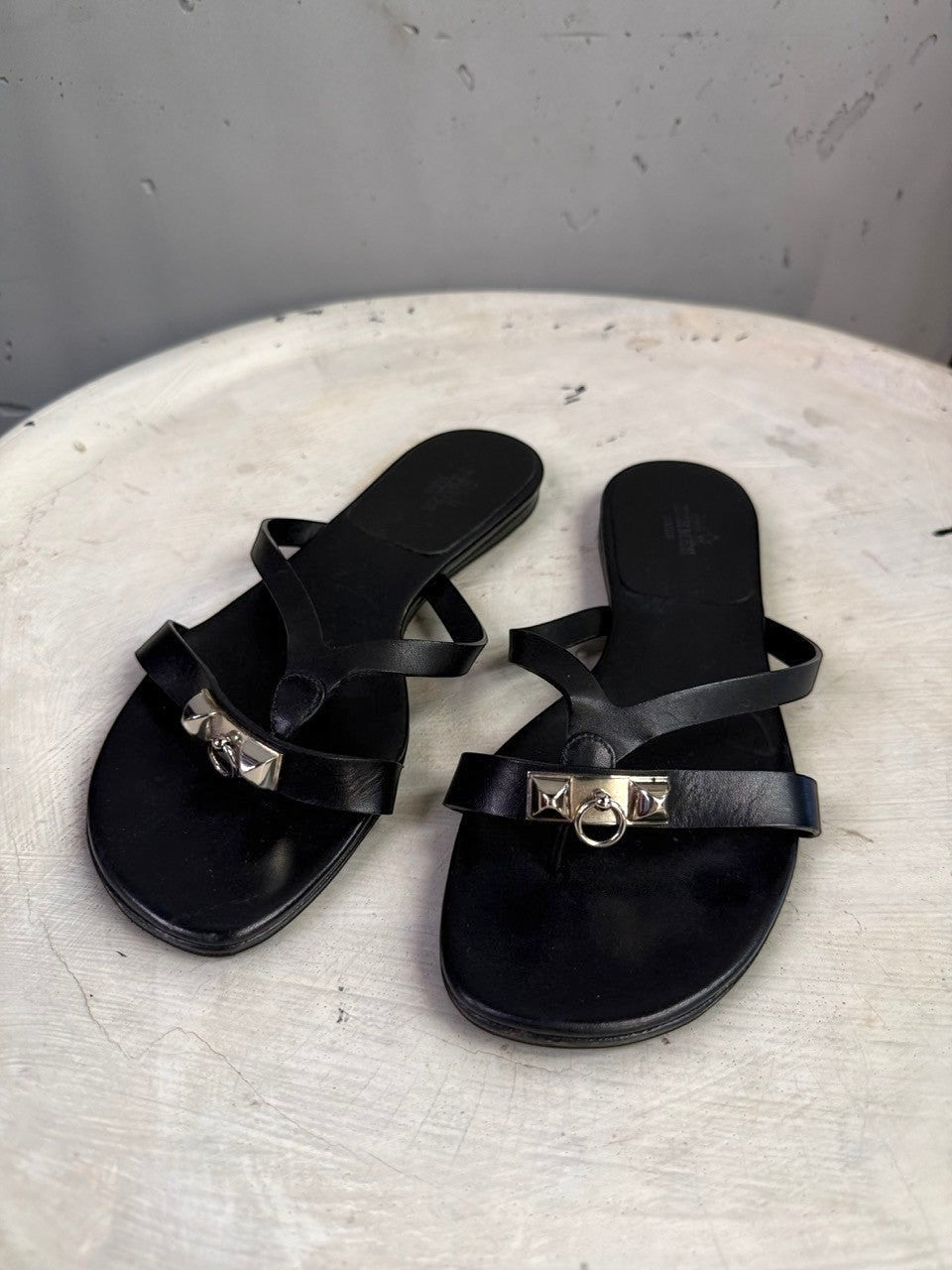 BERLIN VINTAGE CORNER black leather thong sandals featuring iconic metallic hardware and a sleek minimalist design.