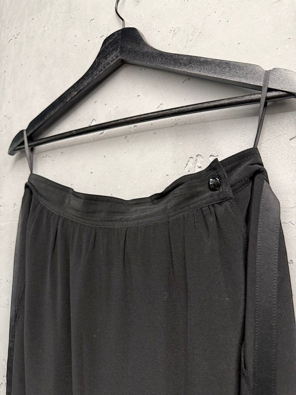 BERLIN VINTAGE CORNER black midi skirt with satin side panels and button closure, flowing fabric.