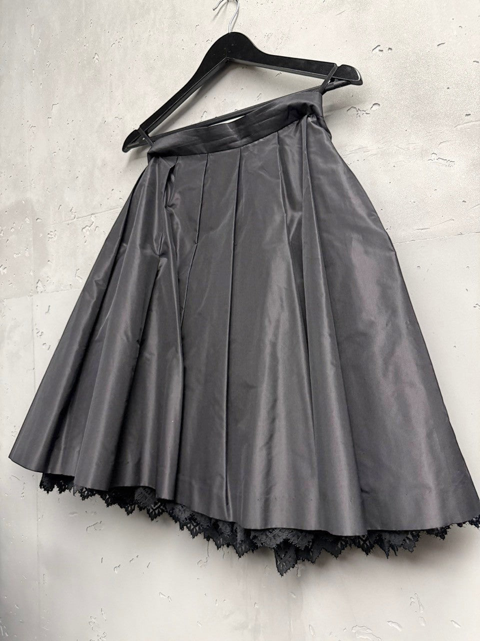 BERLIN VINTAGE CORNER black midi skirt with pleats and lace trim, satin-like fabric, A-line silhouette, hidden tulle layer.