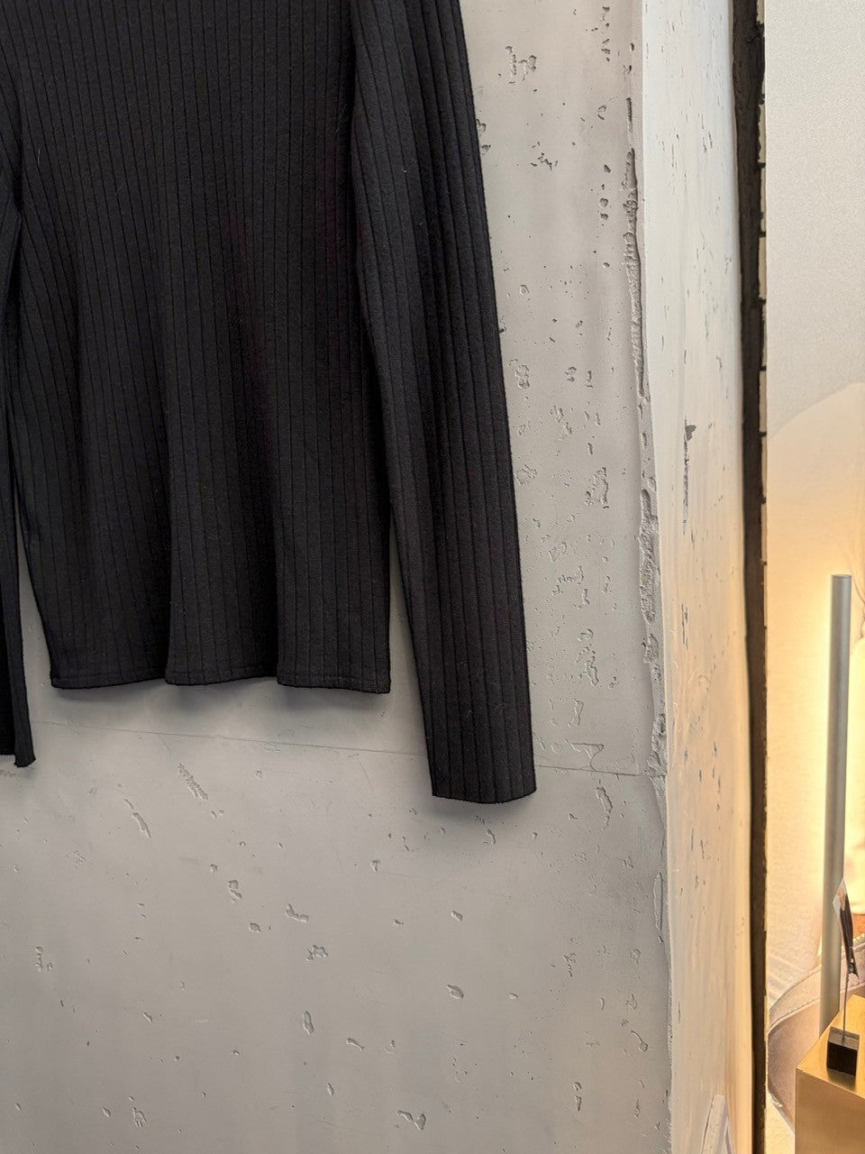 BERLIN VINTAGE CORNER black ribbed knit mock neck long sleeve top with gold-tone button detail on shoulder.