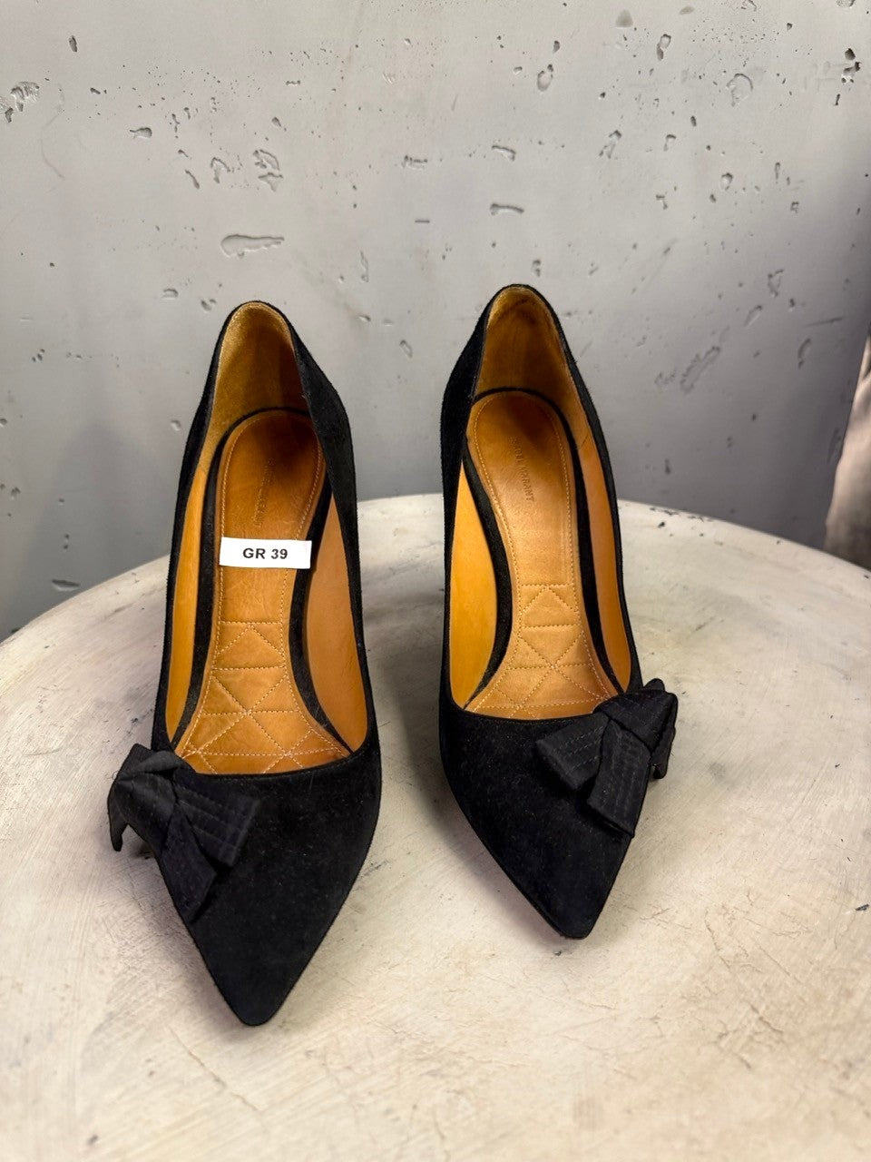 BERLIN VINTAGE CORNER black suede stiletto pumps with pointed toe and bow detail on a white textured surface