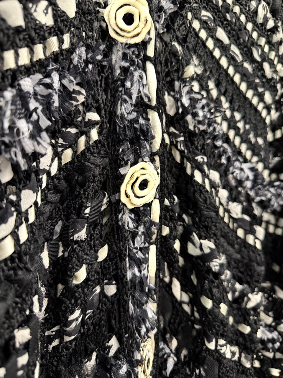 BERLIN VINTAGE CORNER black and white open-weave knit cardigan with rosette buttons and fringe details.