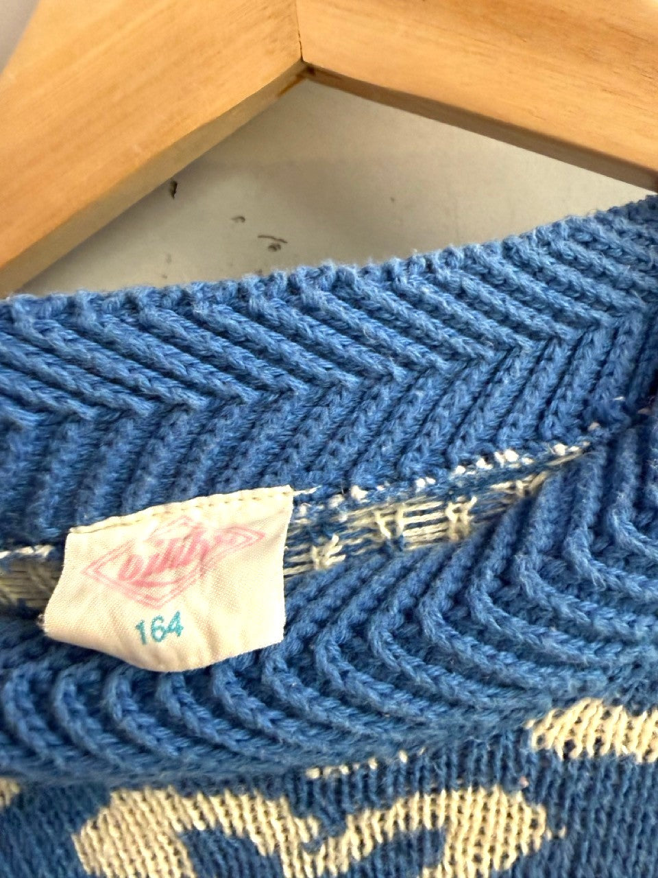 BERLIN VINTAGE CORNER blue knit sweater with abstract white floral pattern and striped cuffs. Ribbed crew neck.