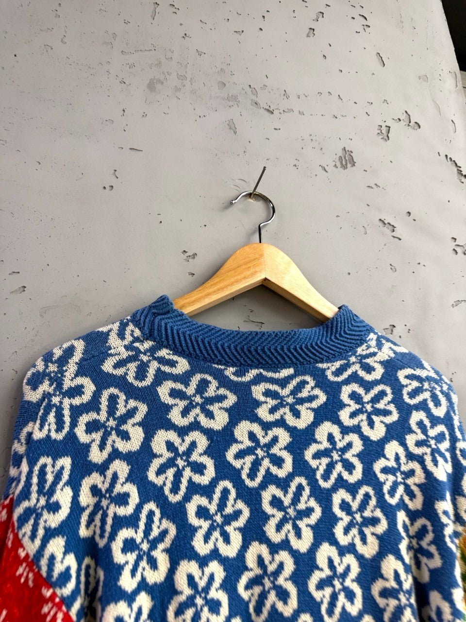 BERLIN VINTAGE CORNER blue knit sweater with white abstract floral pattern and red/green accents.