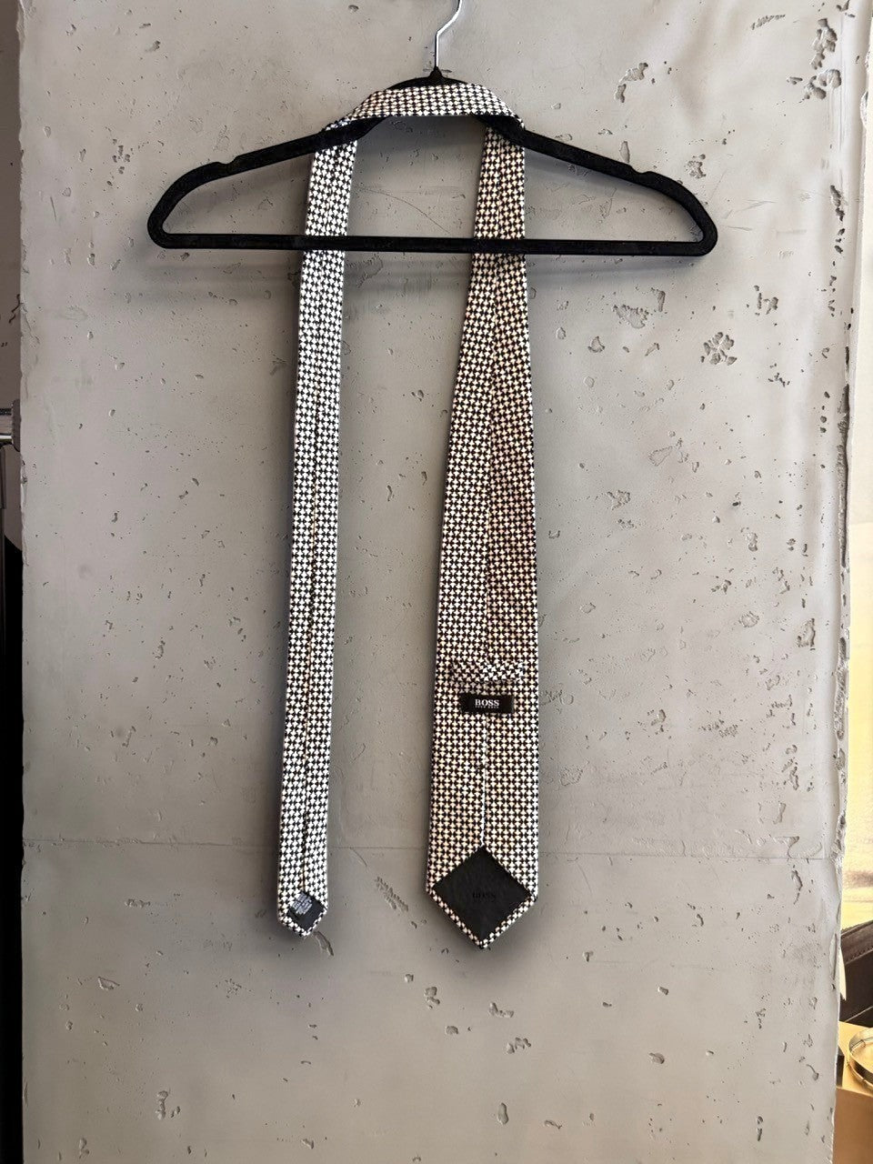 BERLIN VINTAGE CORNER BOSS Hugo Boss formal necktie featuring a black and white geometric micro-pattern on a hanger.
