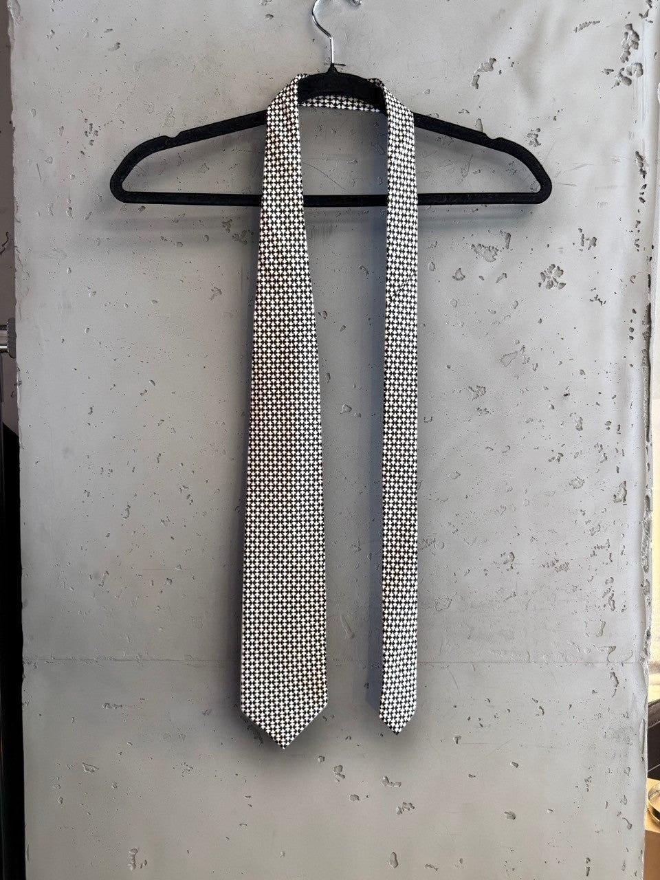 BERLIN VINTAGE CORNER BOSS Hugo Boss formal necktie featuring a black and white geometric micro-pattern on a hanger.