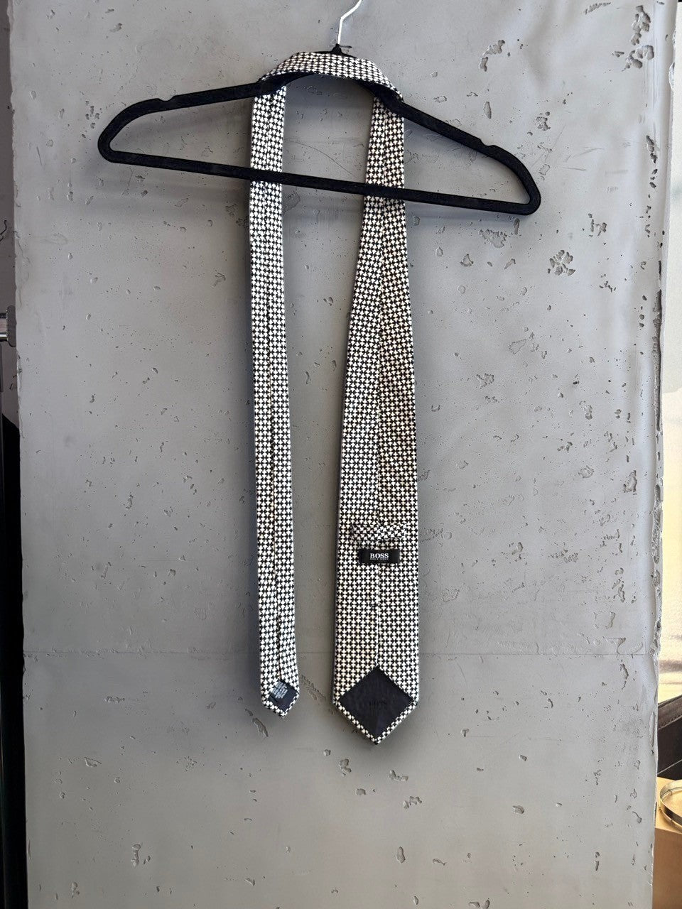 BERLIN VINTAGE CORNER BOSS Hugo Boss formal necktie featuring a black and white geometric micro-pattern on a hanger.