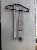 BERLIN VINTAGE CORNER BOSS Hugo Boss formal necktie featuring a black and white geometric micro-pattern on a hanger.