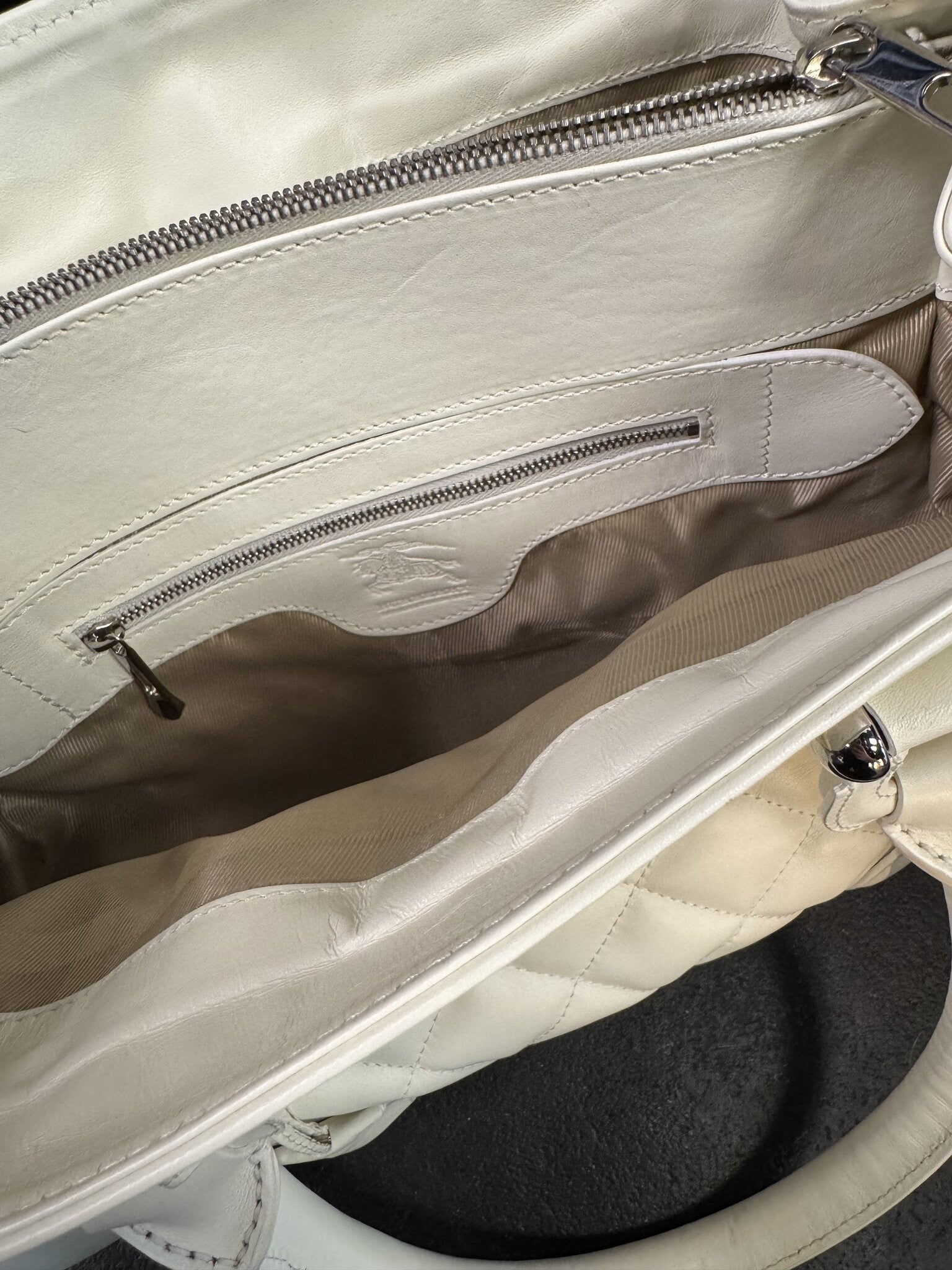 Interior of a BERLIN VINTAGE CORNER white quilted leather Burberry handbag featuring a zippered pocket and fabric lining