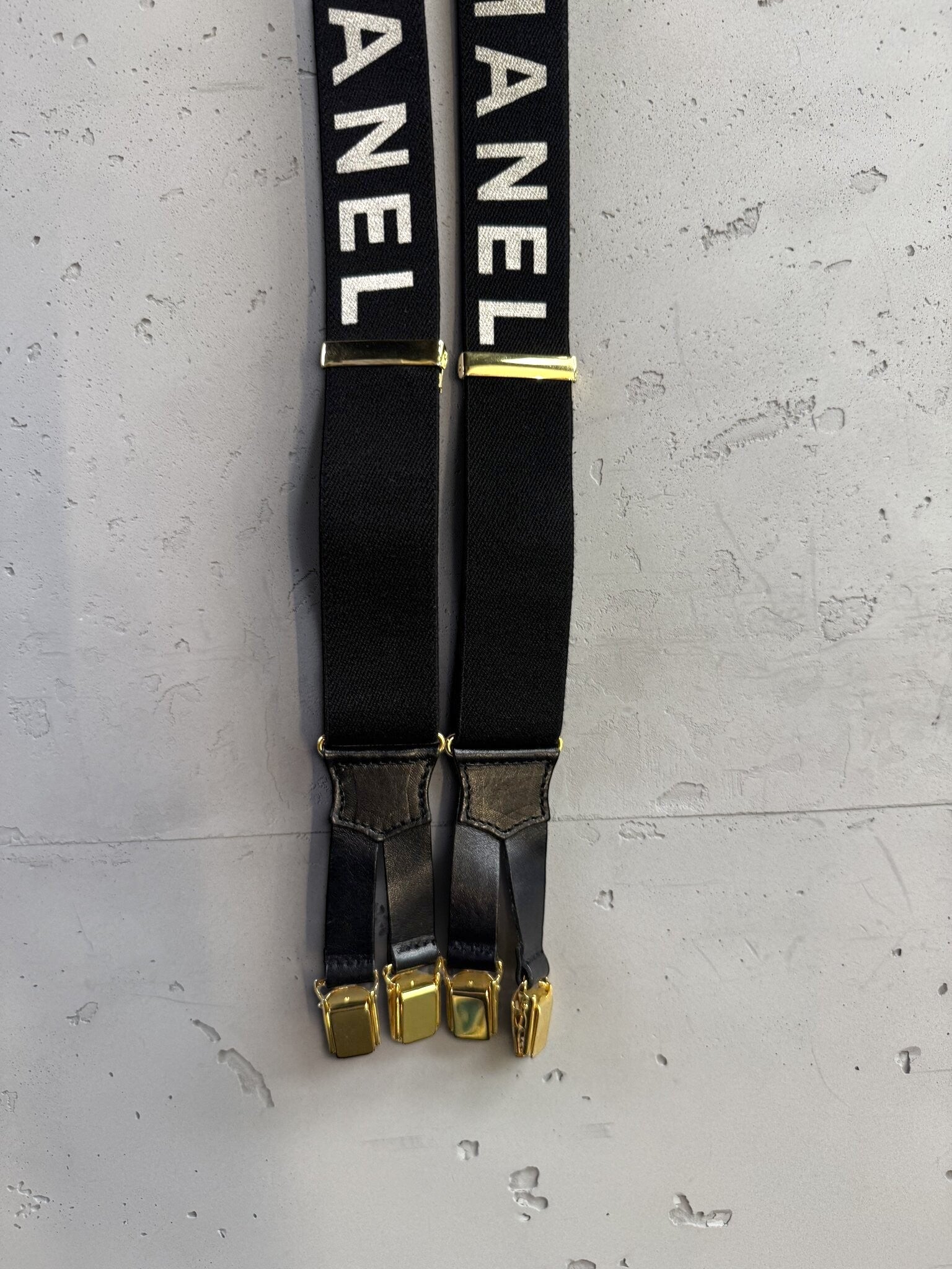 BERLIN VINTAGE CORNER black elastic CHANEL suspenders with white logo text, gold-tone hardware, and leather detailing.