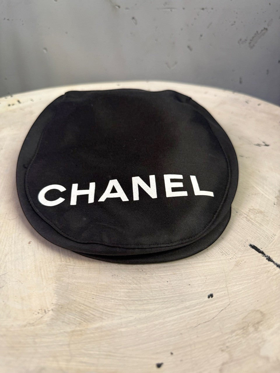 BERLIN VINTAGE CORNER black CHANEL newsboy cap with bold white lettering on a textured surface