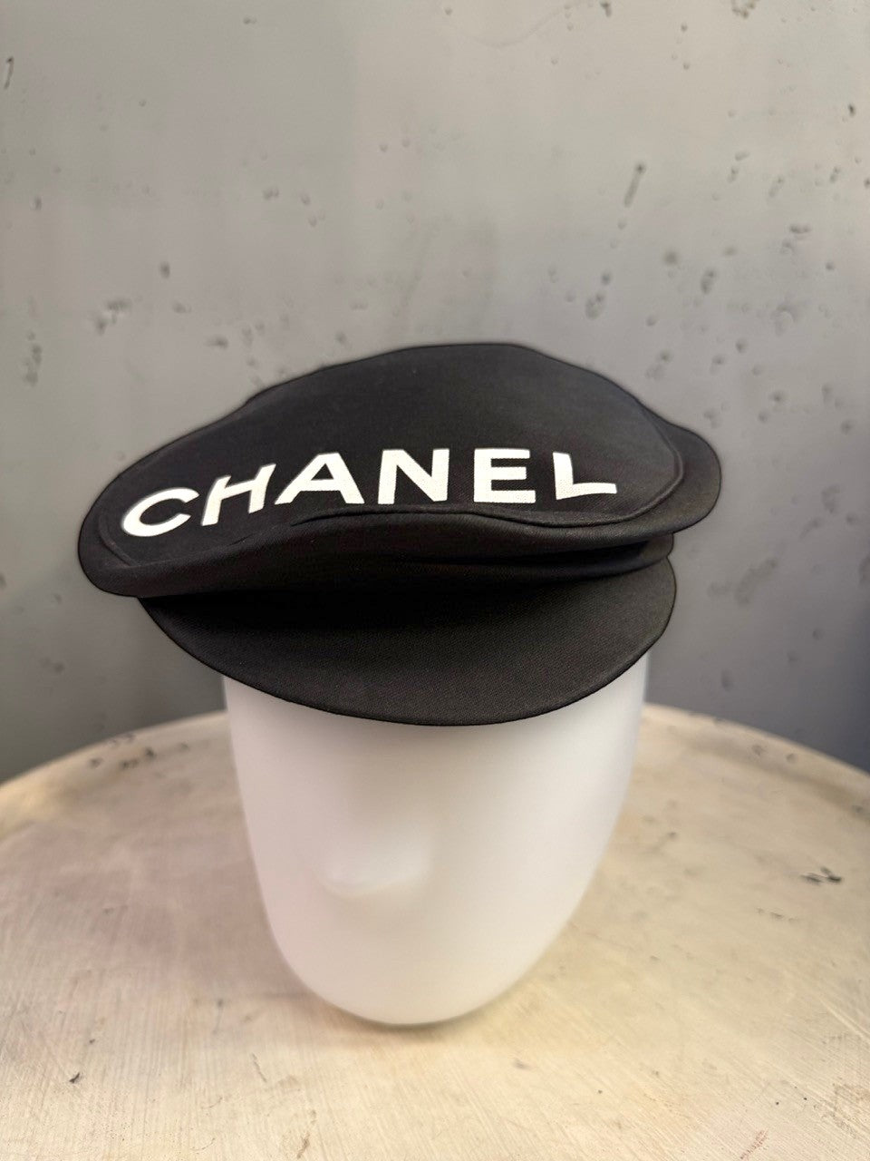 BERLIN VINTAGE CORNER black CHANEL newsboy cap with bold white lettering on a white mannequin head