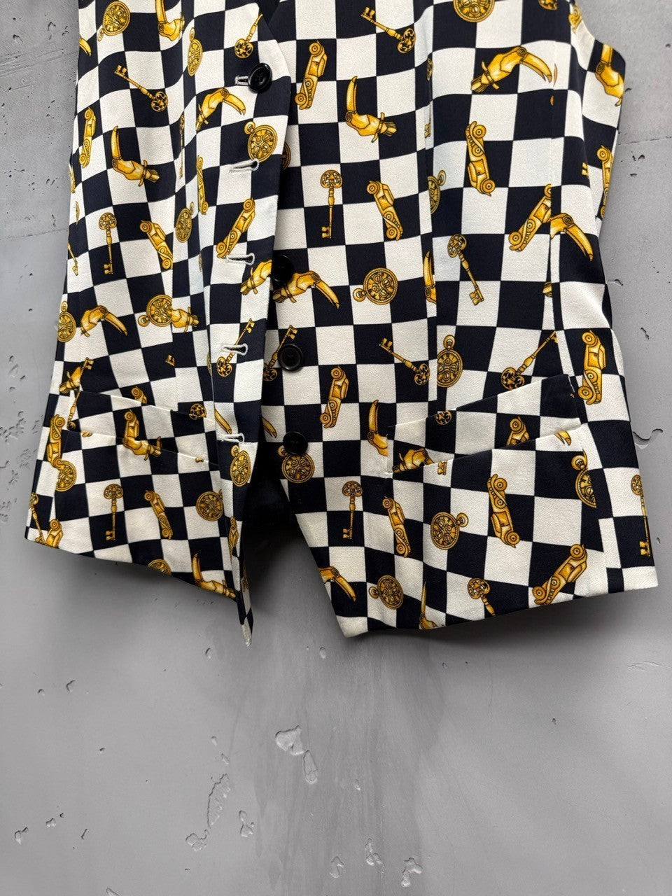 BERLIN VINTAGE CORNER black and white checkerboard vest with gold key and clock print. Sleeveless V-neck with button front.