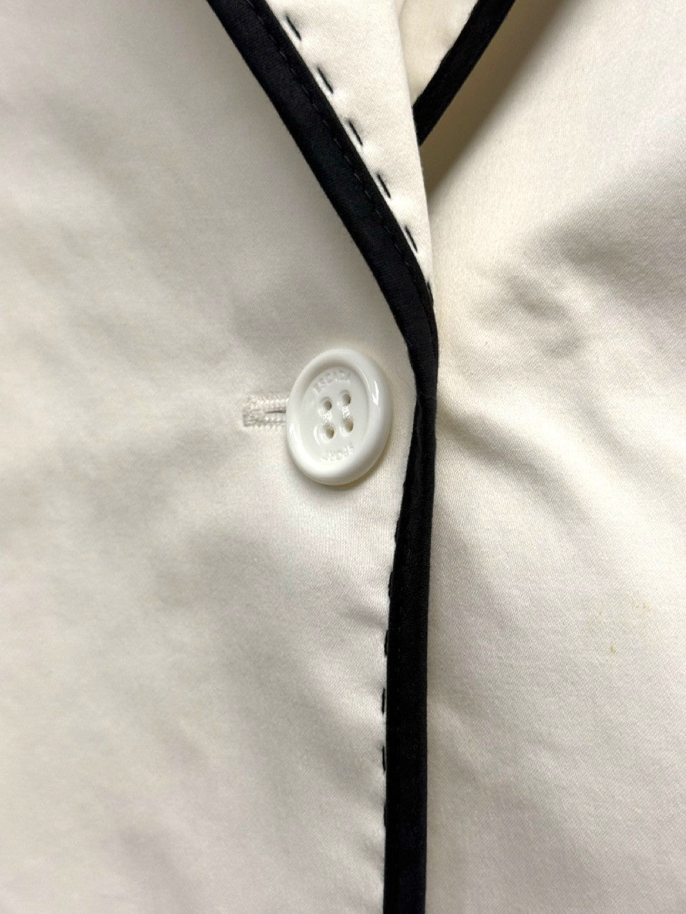BERLIN VINTAGE CORNER cream blazer with black piping and a white button. Classic single-button closure.