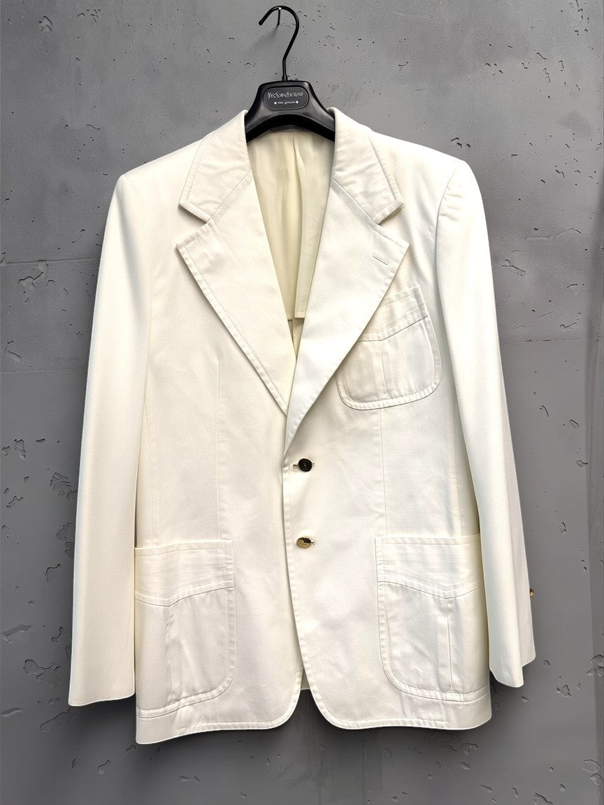 BERLIN VINTAGE CORNER cream cotton blend blazer with two-button closure, gold-tone buttons, notched lapel, and patch pockets.