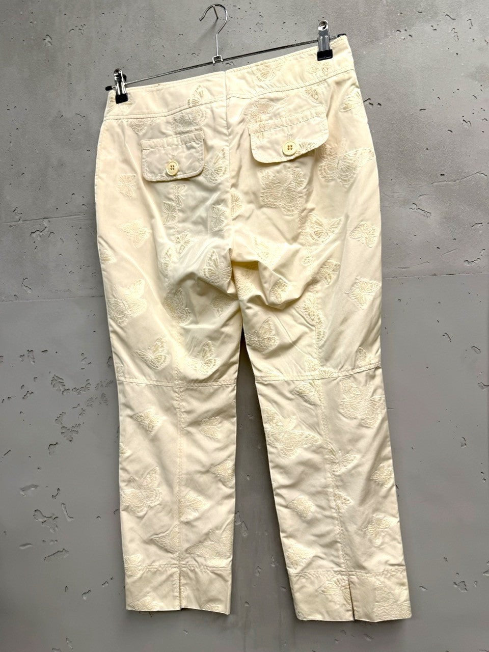 BERLIN VINTAGE CORNER cream trousers with all-over embroidered butterfly pattern, tailored fit, and button-fly closure.