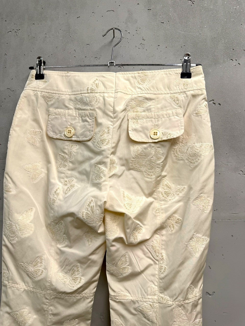 BERLIN VINTAGE CORNER cream trousers with all-over embroidered butterflies and button-flap back pockets.