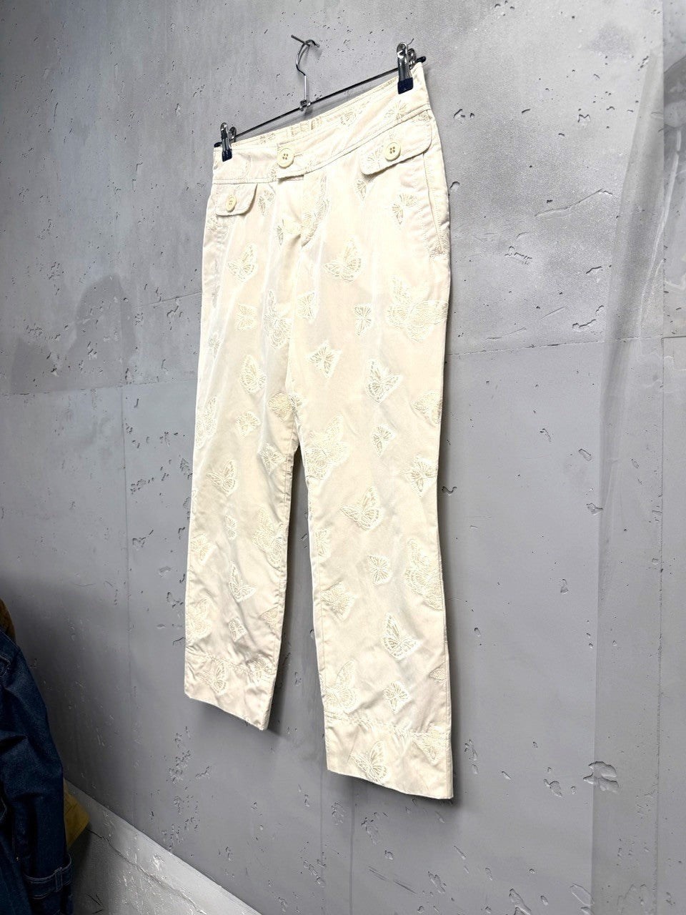 BERLIN VINTAGE CORNER cream trousers with all-over white butterfly embroidery, button-fly closure, and tailored fit.