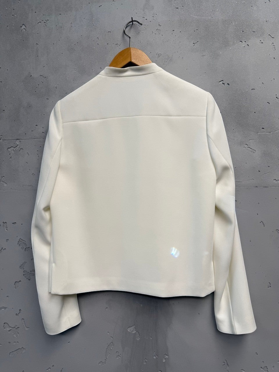 BERLIN VINTAGE CORNER cream cropped jacket with collarless neckline and hook-and-eye closure, made from smooth structured fabric.