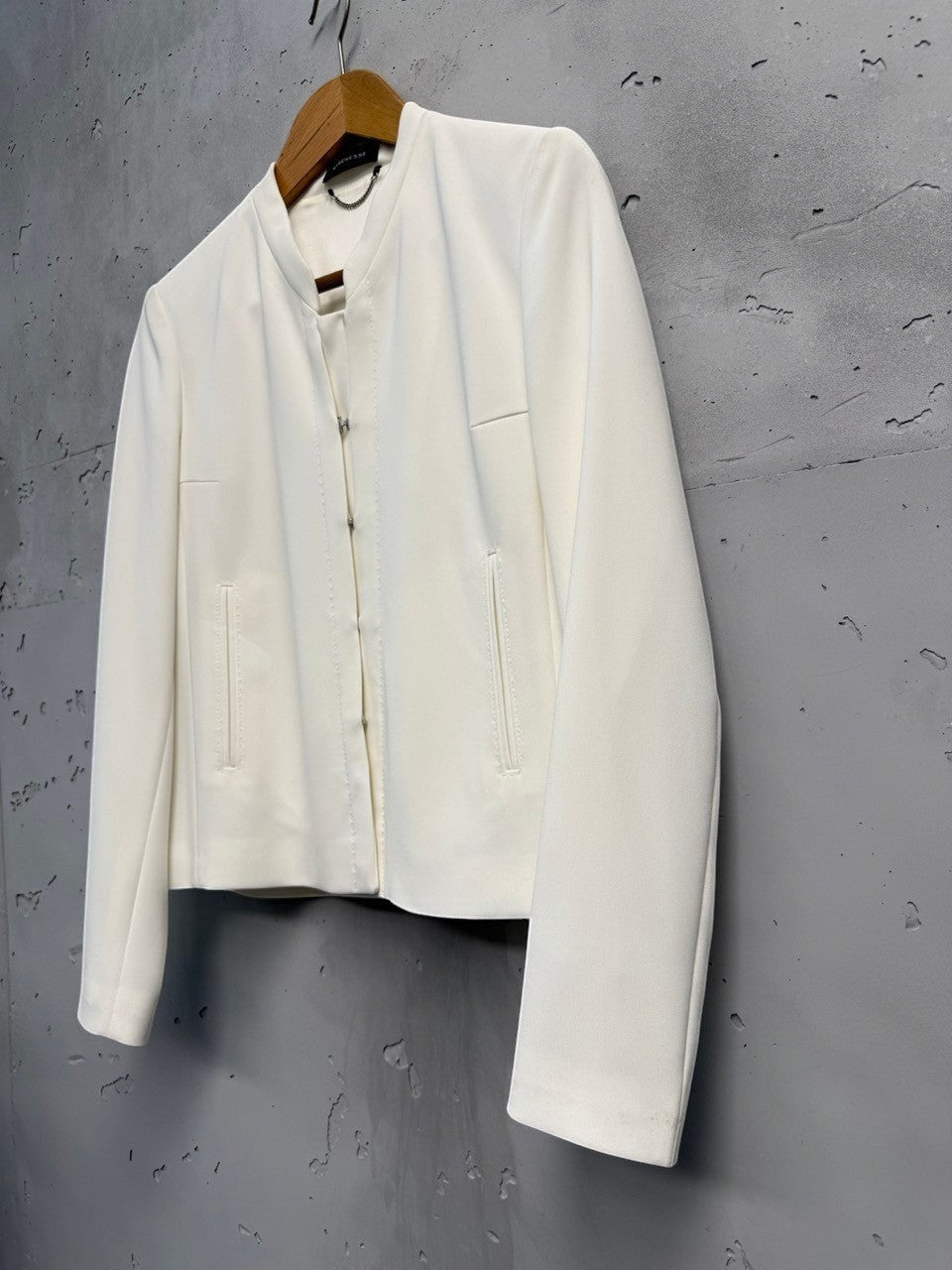 BERLIN VINTAGE CORNER cream cropped jacket with collarless neckline and hook-and-eye closure, made from smooth structured fabric.