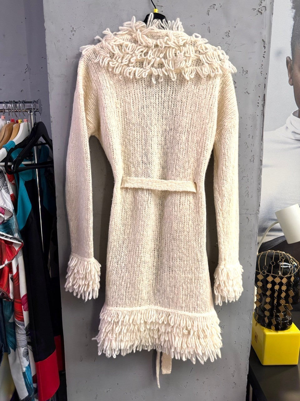 BERLIN VINTAGE CORNER cream chunky knit long cardigan with fringe trim on collar, cuffs, and hem and a tie-waist belt.