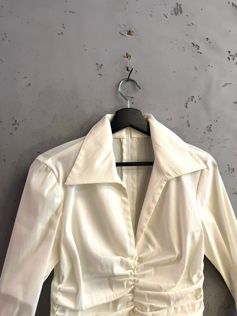 BERLIN VINTAGE CORNER cream long sleeve blouse with a pointed collar and ruched front detailing on a hanger.