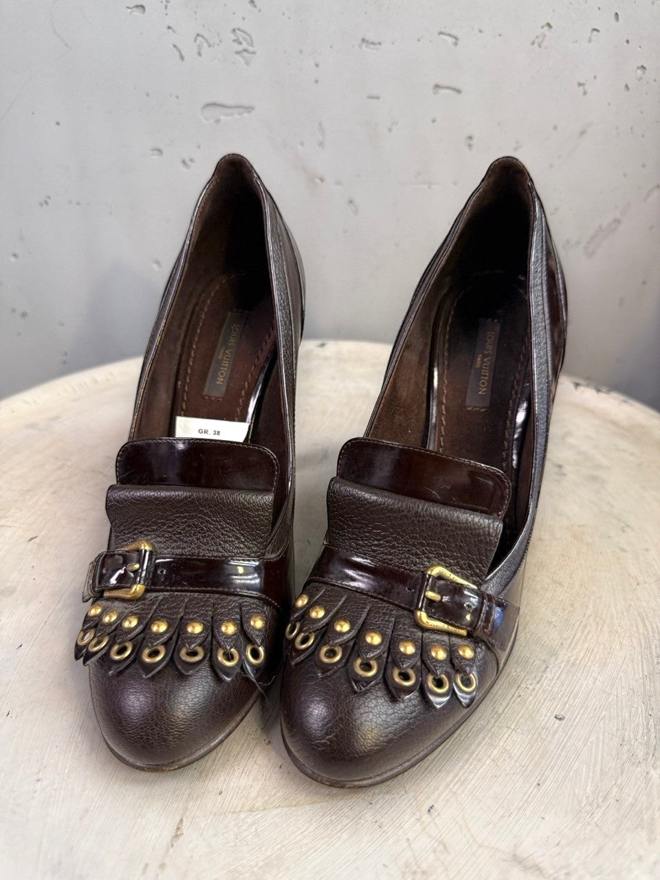 BERLIN VINTAGE CORNER dark brown leather loafer heels with fringe, gold hardware, and buckle detail.