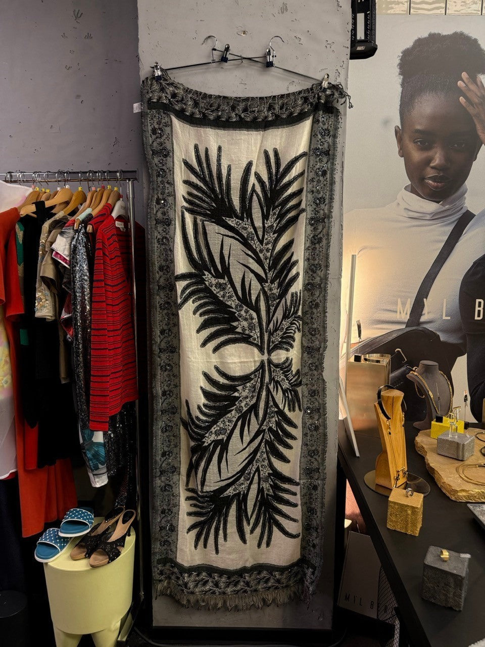 BERLIN VINTAGE CORNER cream and black botanical print scarf with beaded border and frayed edges in a boutique setting.