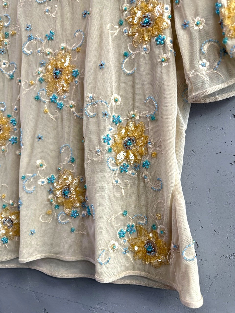 BERLIN VINTAGE CORNER sheer mesh blouse with short sleeves, embellished with gold and turquoise floral embroidery, beads, and sequins.