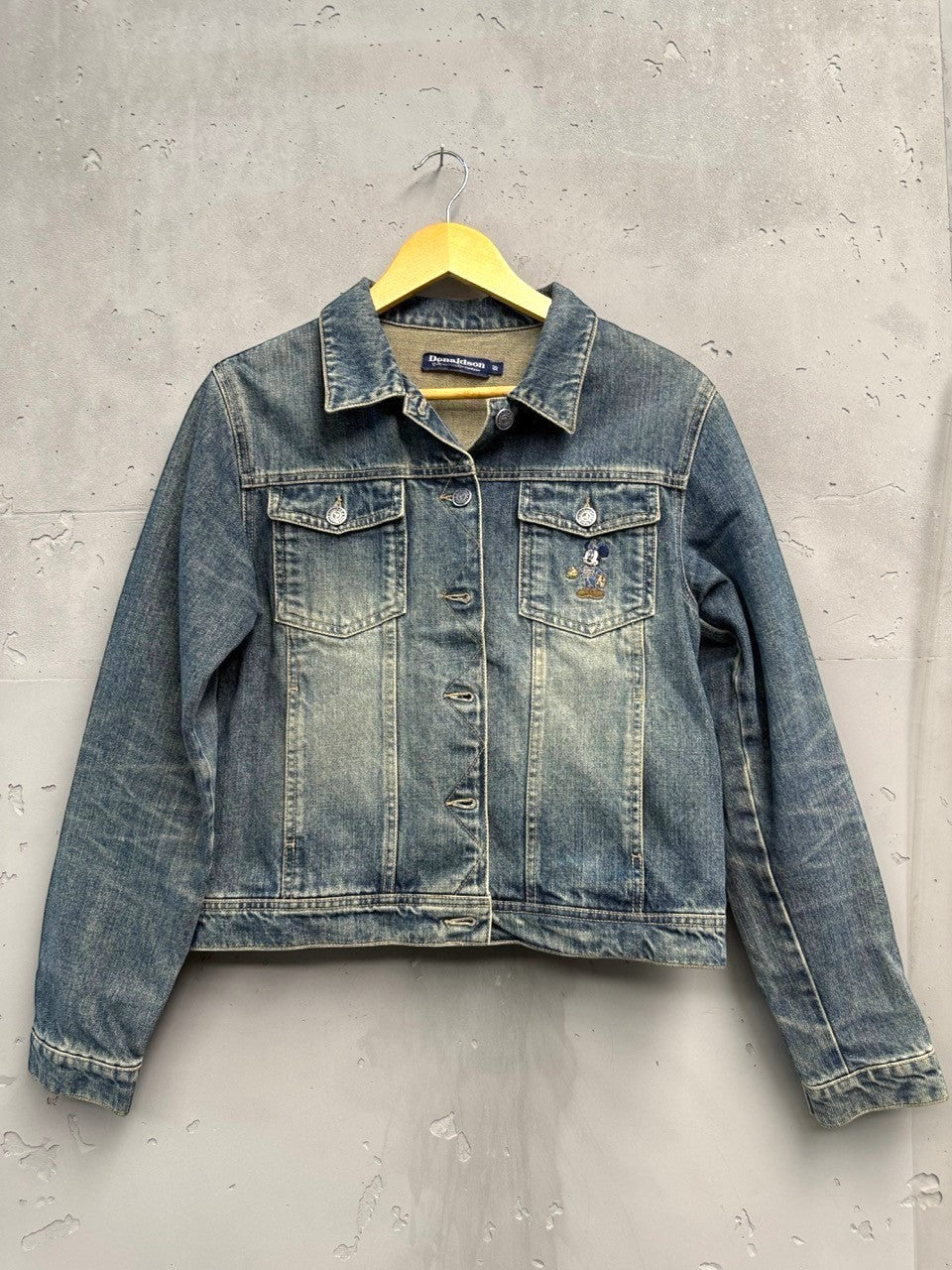 BERLIN VINTAGE CORNER blue washed denim trucker jacket with embroidered Mickey Mouse motif on chest pocket.
